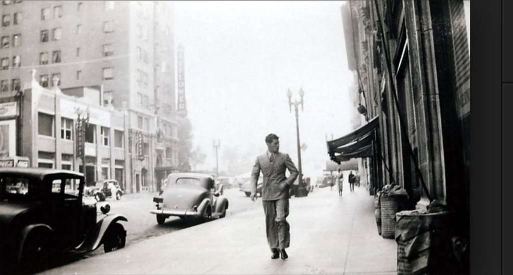 A young gentleman headed south on Grand Avenue across from the Mayflower Hotel, 1937