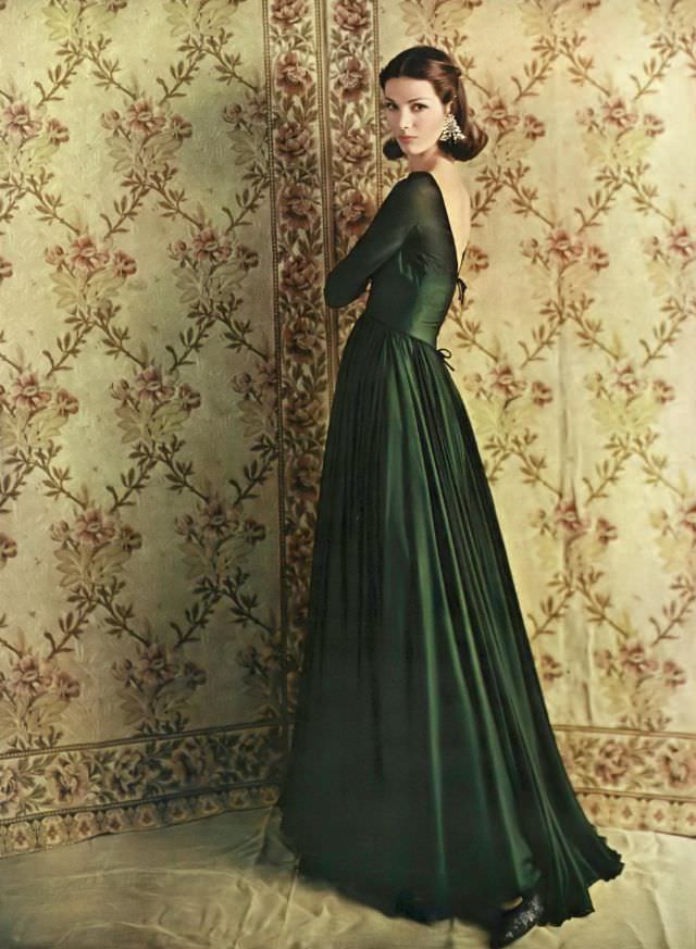 Pia Kazan in spectacular dress of silk chiffon in two layers of black over forest green with a deep V-back, by Scaasi who also designed the earrings, Vogue, October 1, 1960
