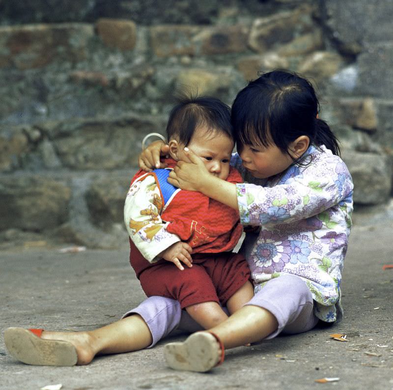 Girl looking after her little brother, Kao Sai Chau, 1978