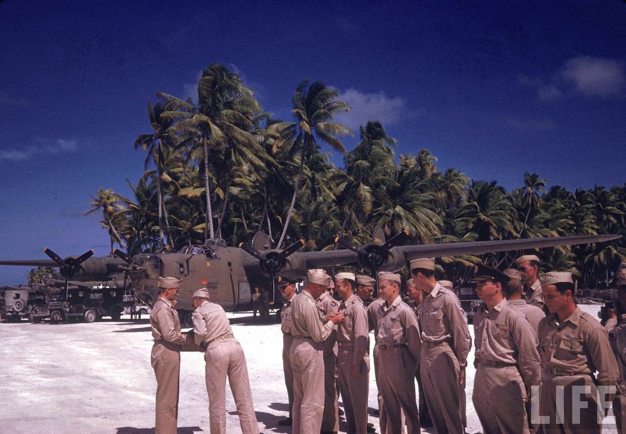 Small group of servicemen getting medals at an airstrip ceremony during WWII.