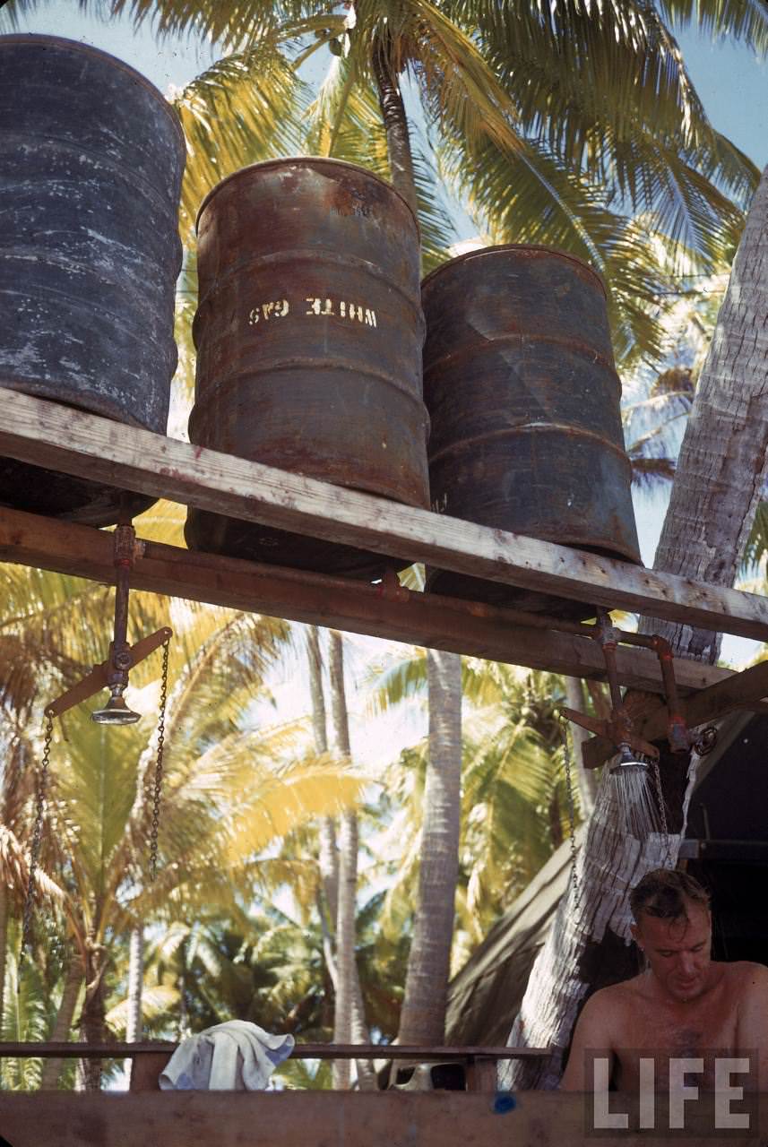 Soldier using a makeshift shower on Tarawa during WWII.