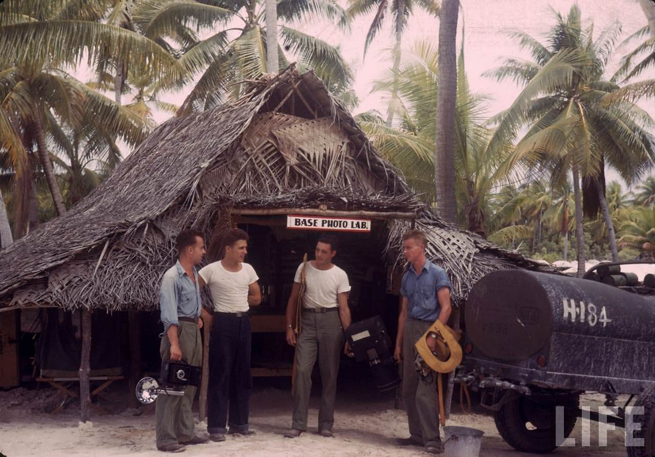 Group of servicemen (?) gathered in front of a photo processing lab on an island base during WWII.