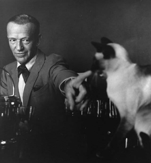 Fred Astaire pointing at his Siamese cat, 'Carlyle,' 1962