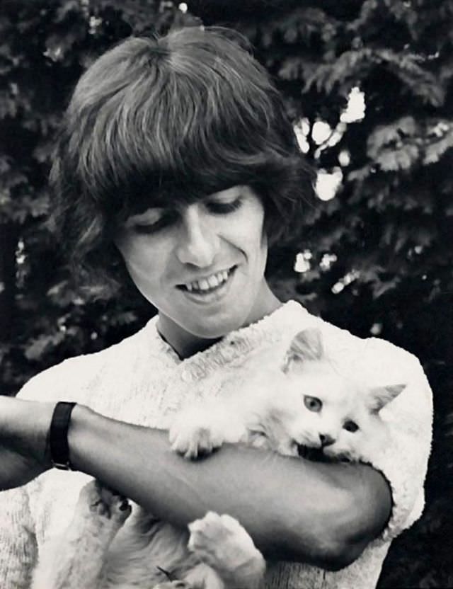 George Harrison with his cat, 'Corky,' by the pool at Kinfauns, Surrey, England, 1965.