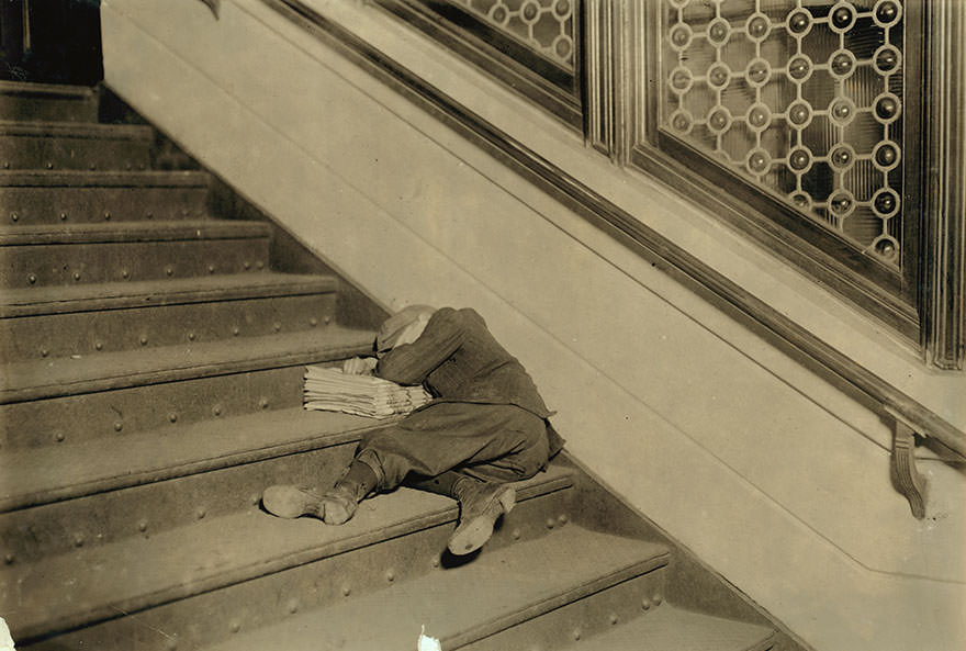 Newsboy asleep on stairs with papers. Location: Jersey City, New Jersey