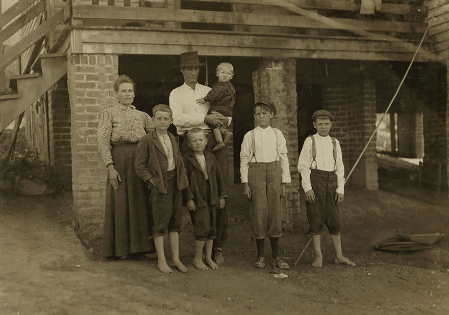 S.D. Ison and family. Father works some. Both boys on right of photo have been in Washington cotton mills, fries, va., for four years. When i asked the smallest worker how old he was, he said, “don’t know,” and looked at his father, who said, “going’ on 14.” Location: fries, Virginia