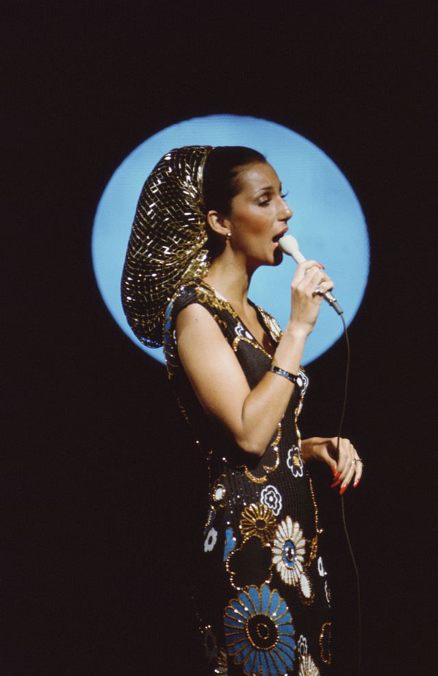 Promotional portrait of Cher as she sings into a microphone for the television variety show 'The Sonny and Cher Comedy Hour, 1972