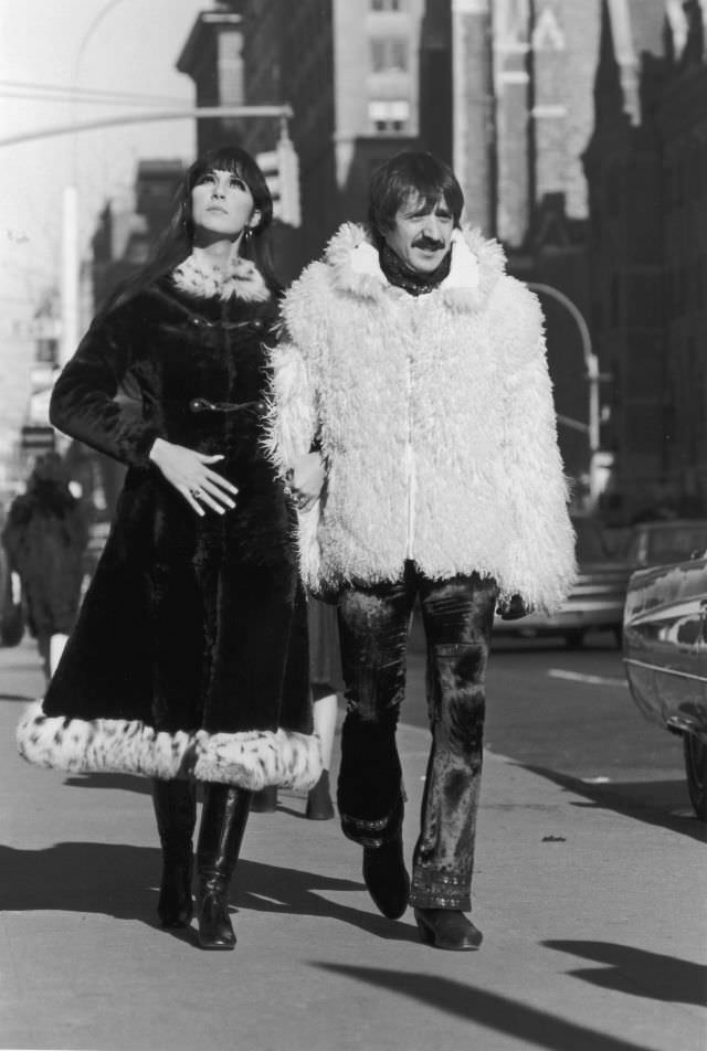 Sonny Bono, in a Mongolian lamb's wool jacket, and Cher, in a long fur overcoat trimmed with leopard fur, walk arm-in-arm down the sidewalk, New York City. Photo by Jack Robinson.