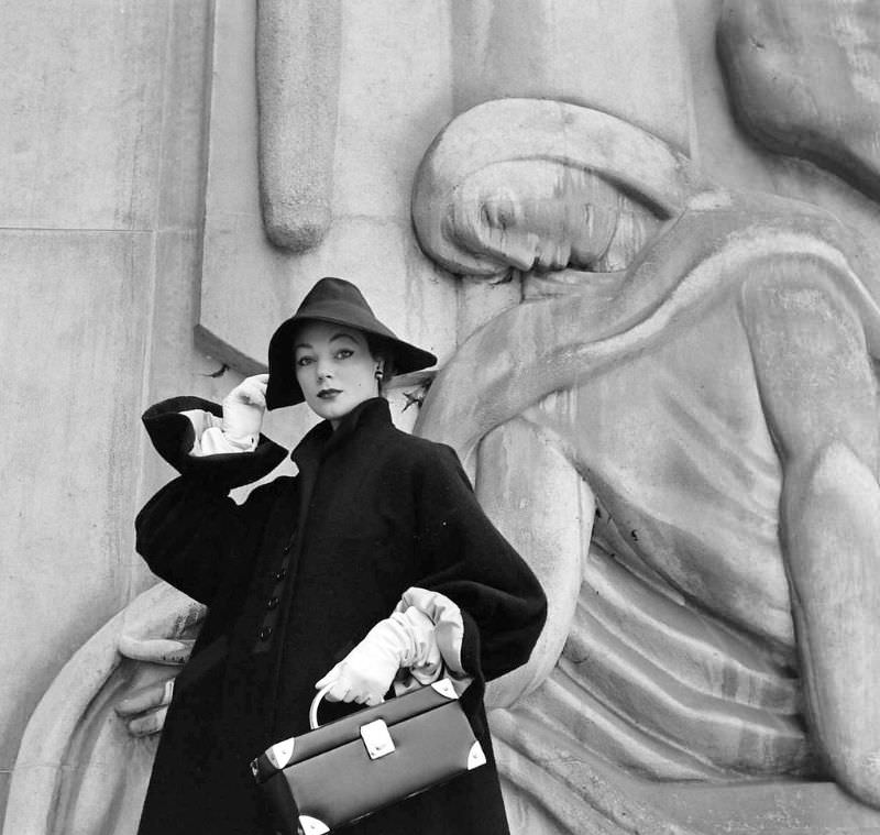 Ivy is wearing Givenchy's big-sleeved coat of navy wool with new wrist-ruffle cuffs and Garbo-slouch hat, Paris, February 1952