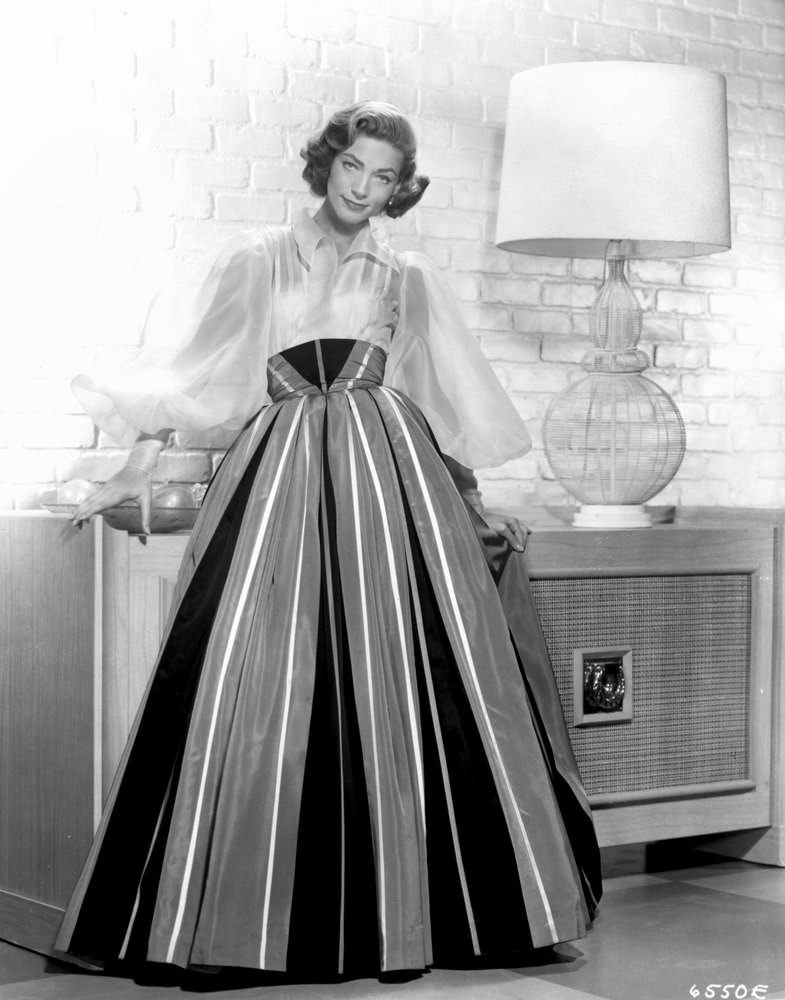 Looking elegant in a billowy blouse and high-waist full skirt for a studio portrait, 1955.