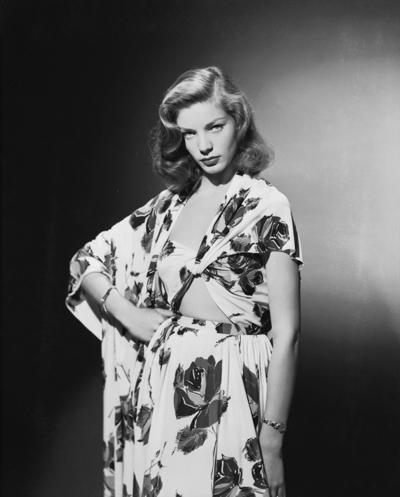 Wearing a bold floral print dress with just the right amount of skin showing, 1944.