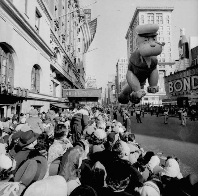 Helium-filled Popeye balloon figure floats above some of the 1,300,000 persons watching the 33rd Macy's Thanksgiving Day Parade pass through Times Square, New York, November 26, 1959.