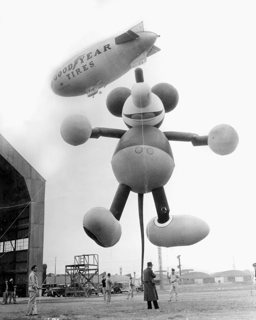 This giant Mickey Mouse balloon, shown tied to dirigible at Glendale in 1934, Calf., was a feature of Macy's Thanksgiving Day parade, escorting Santa Claus into New York.