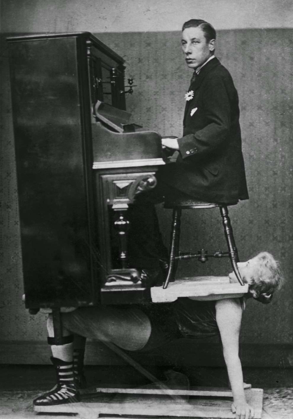 A strongwoman balances a piano and pianist on her chest, 1920