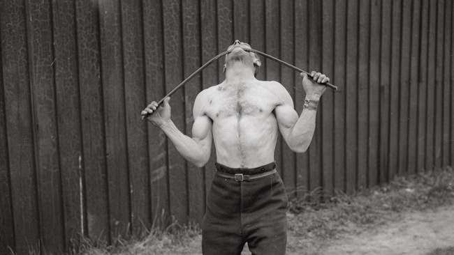 George Challard bending an iron bar with his teeth, 1935