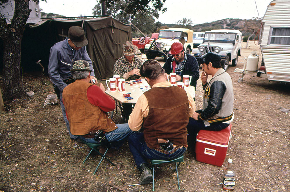 Deer hunters drink and play poker while waiting for deer. The hunters have built a permanent camp to which they return each year, November 1972. (Marc St. Gil/NARA)