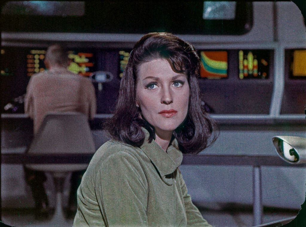 Majel Barrett in her original role from the Star Trek TOS pilot The Cage, as Number One, shown on the original bridge set of the Enterprise.