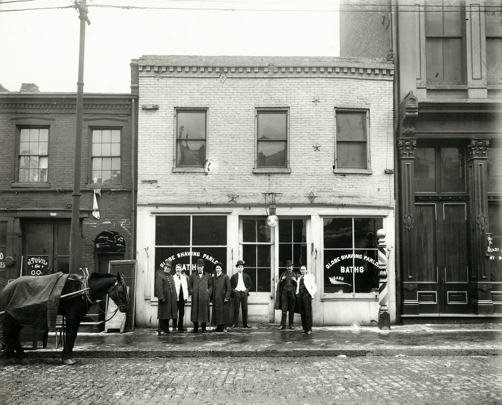 Group of men standing in front of the Globe Shaving Parlor at 1015 Carr Street, ca. 1910