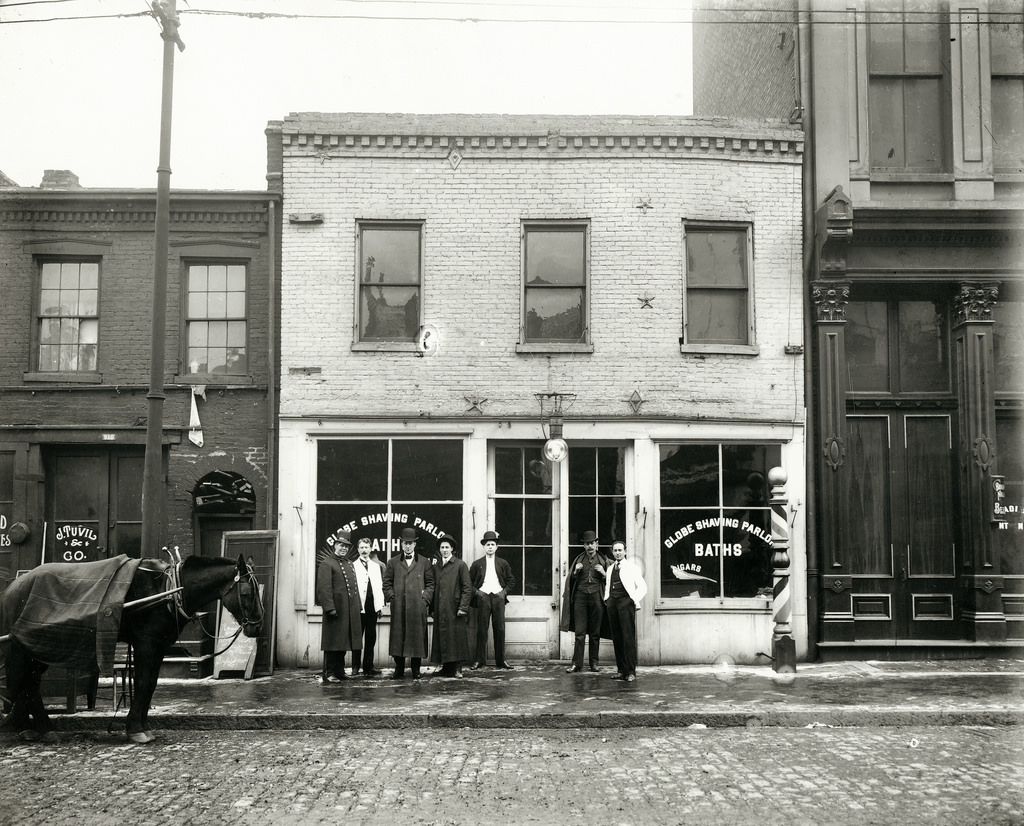 Group of men standing in front of the Globe Shaving Parlor at 1015 Carr Street, ca. 1910