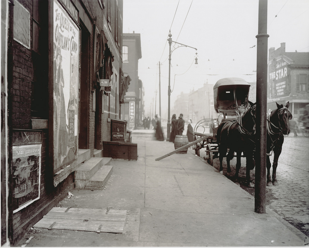 An empty cart for distributing beer in front of a bar on a street, ca. 1900s