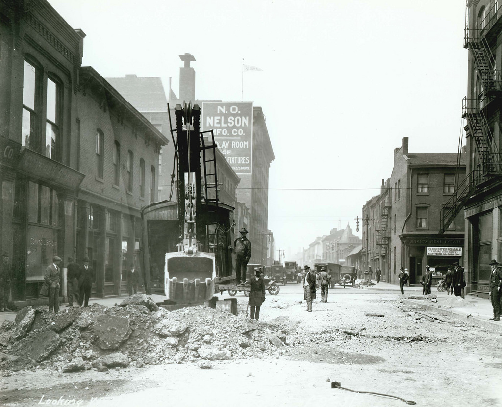 Workers using a crane to tear up the road on Chestnut Street west of Ninth Street, 1914