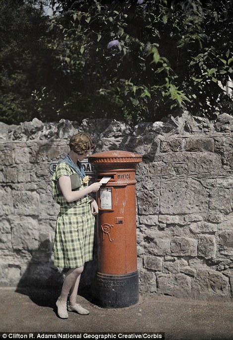 A woman sends a letter at a red pillar box on the Isle of Wight in 1928