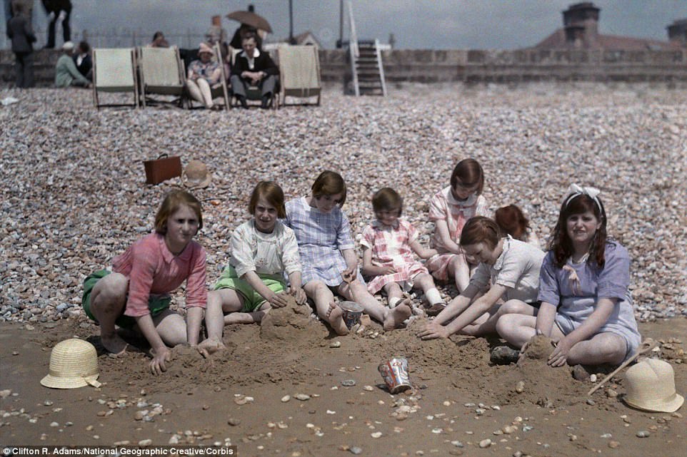 A group of children sit, playing in the sand in 1931 at Dymchurch beach in Kent, which lies south-west of Folkestone