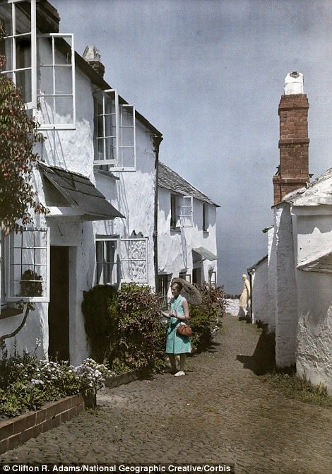 A woman admires flowers in Clovelly, Devon, 1928