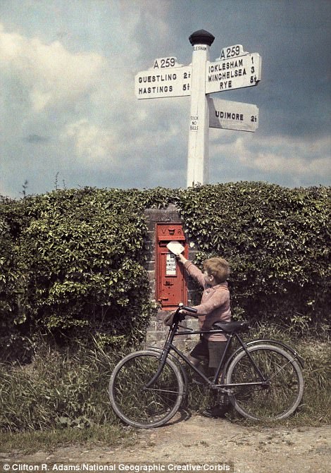 A boy posts a letter in a postbox in Sussex, 1928