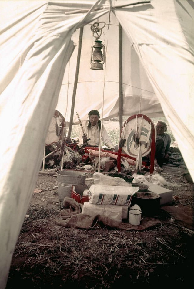 Two Native American men smoke a pipe in their teepee at the campgrounds.