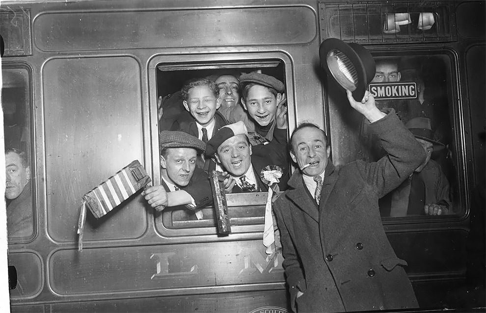 Arsenal football supporters cheering from the train carriage window as they leave Euston Station, London, on their way to Birmingham for their team’s match against Aston Villa which they lost 3-5, 19th November 1932