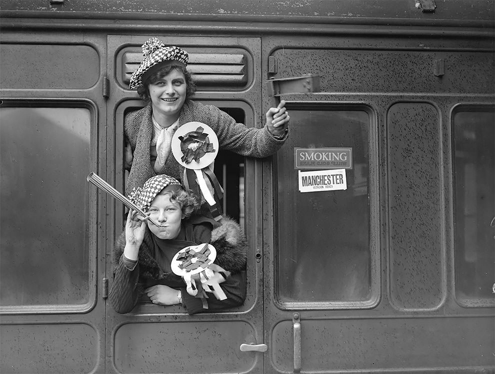 Manchester City FC fans with rattles and rosettes are in a train at Euston which is waiting to take them to White Hart Lane for a cup-tie match against Tottenham Hotspurs, 12th January 1935