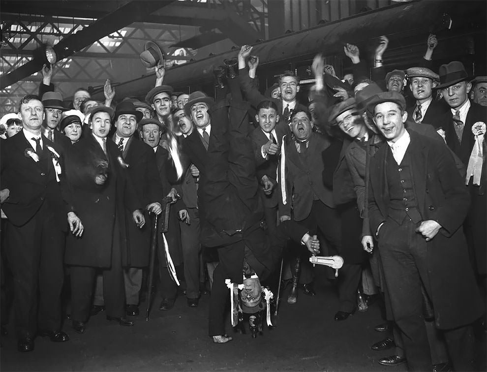 An Arsenal fan performs a one handed handstand at Euston Station to entertain his fellow supporters on their way to Birmingham for the FA Cup replay, 29th January 1930.