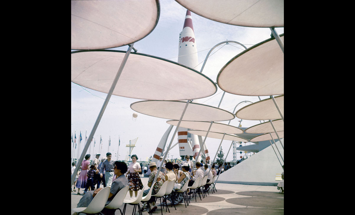 Park attendees relax under sunshades near a TWA rocket in Disneyland in July 1955
