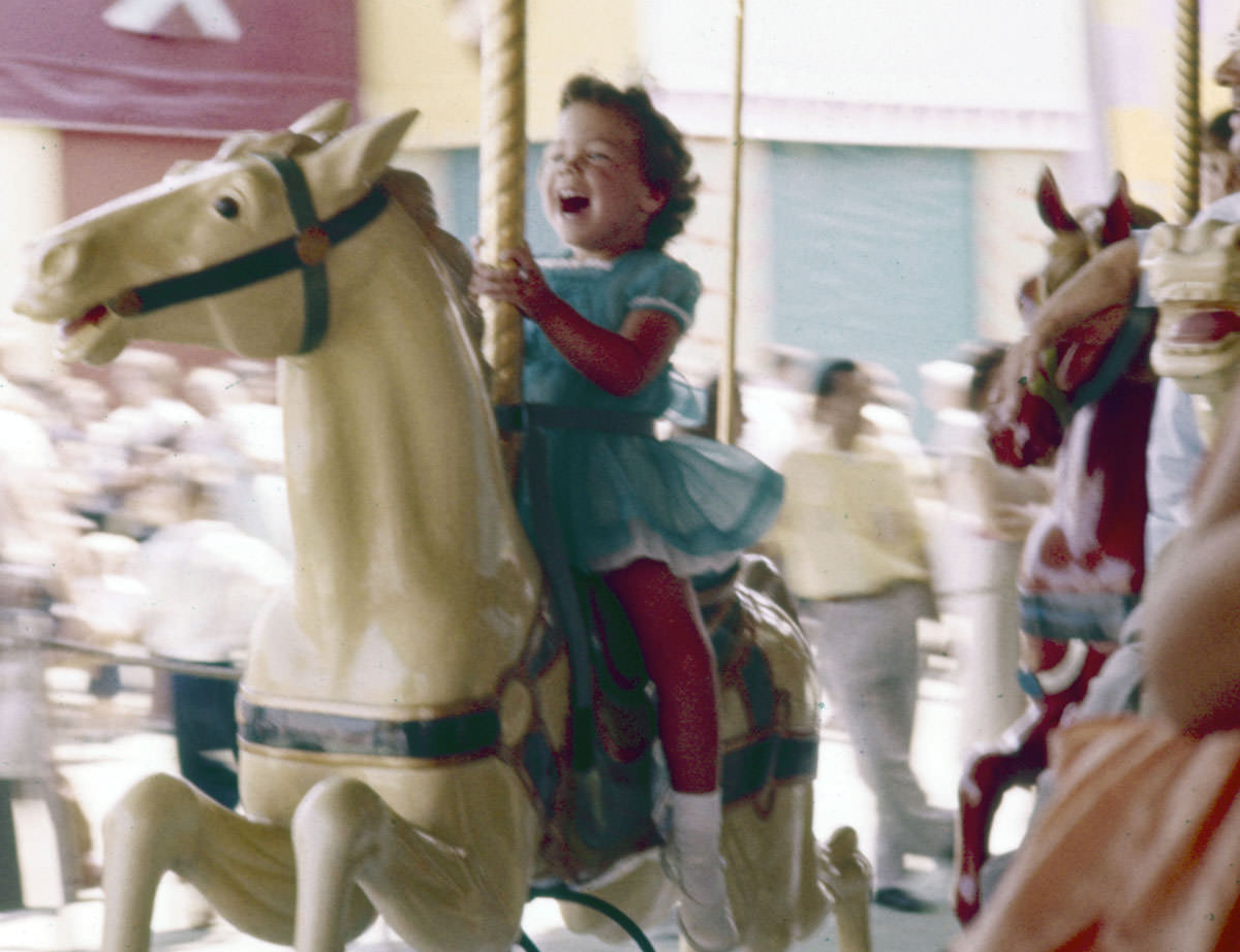 A little girl laughs with excitement while riding a carousel at Disneyland in July 1955