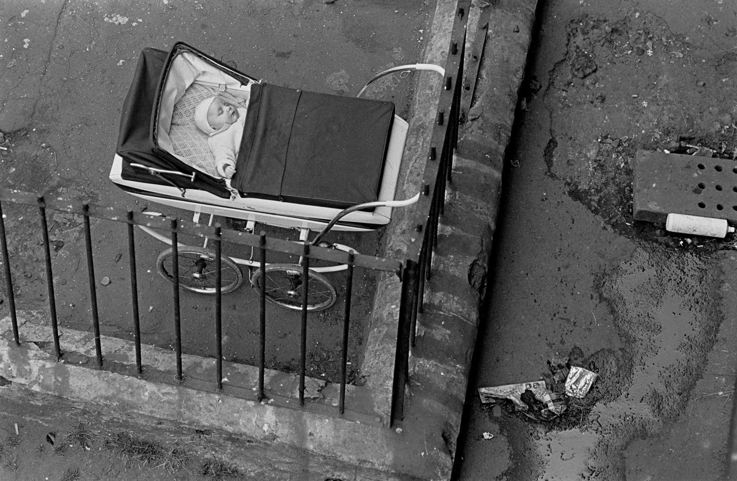 Baby sleeping by the drains in a tenement courtyard Glasgow Maryhill 1971