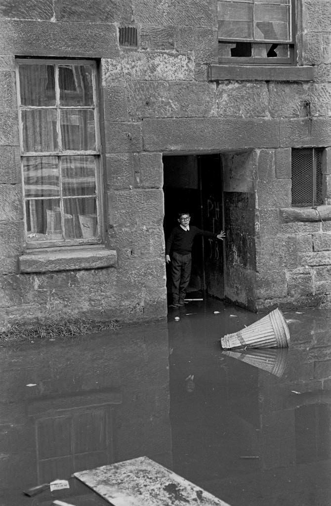 Boy negotiating flooded entry in tenement block Maryhill 1971