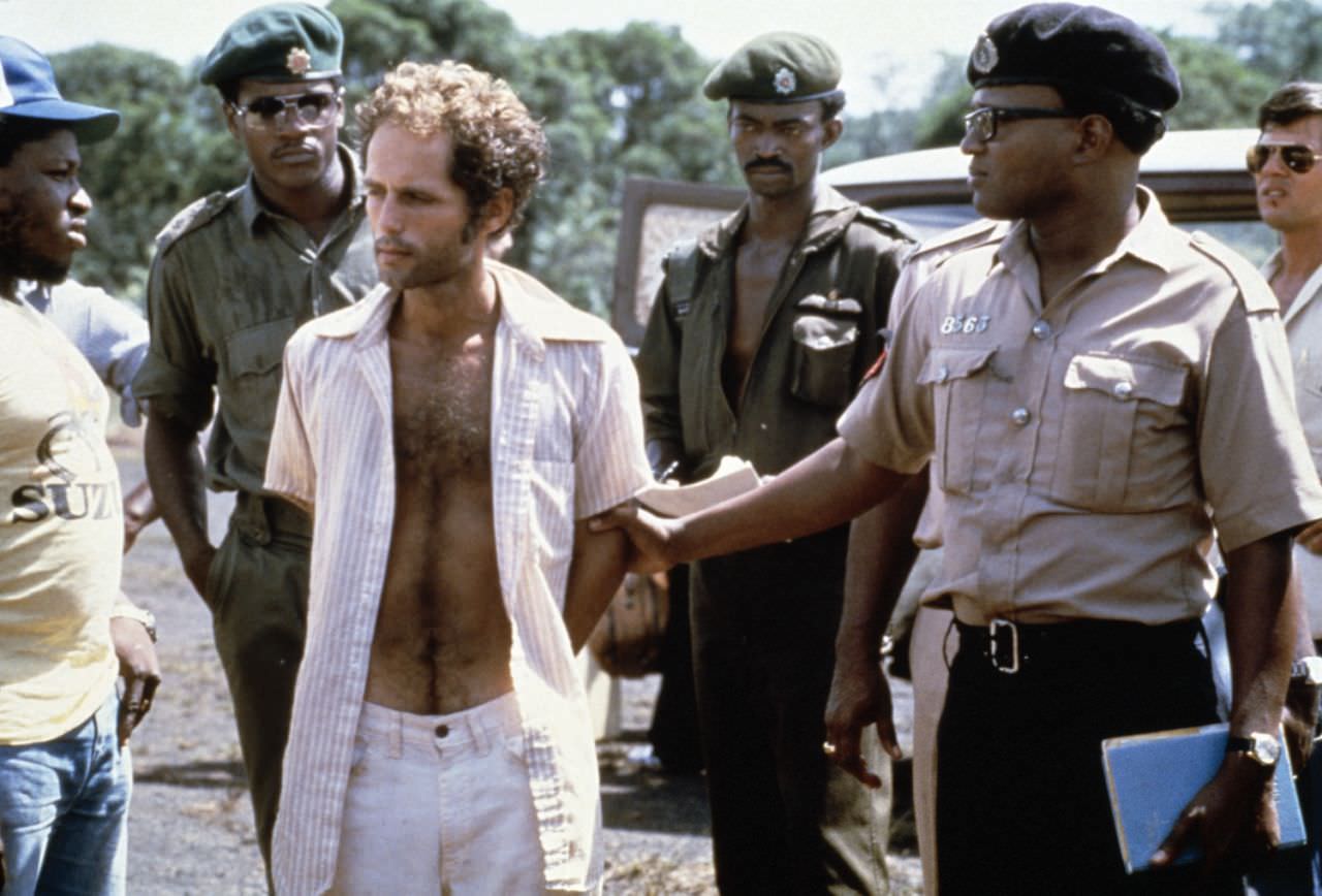 People’s Temple follower Larry Layton, center stands with police following his arrest Nov. 18, 1978 in the shooting of two people on a remote Guyana airstrip.