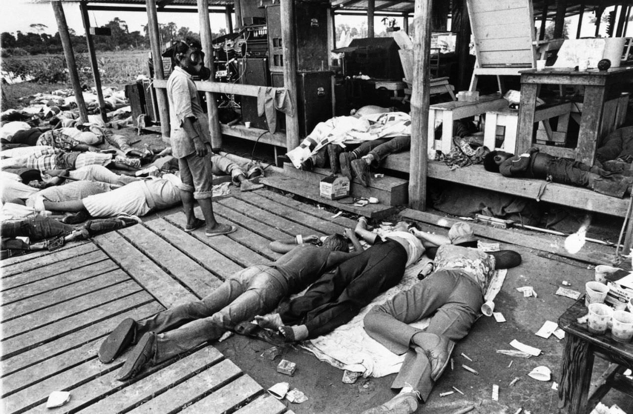 Bodies from a mass suicide victims lie around the pavilion of People’s Temple in Jonestown, Guyana as an onlooker in gas mask stands by, Nov. 18, 1978.