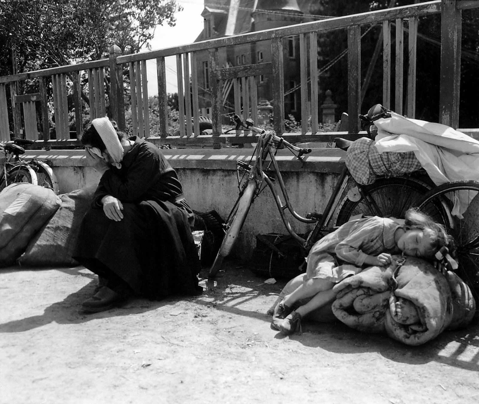 On Aug. 10, 1944, a girl and her grandmother wait in a schoolyard in Saint-Pois, Normandy, France. Refugees fled to Saint-Pois to escape the fighting in Mortaine during the final battle for Normandy.