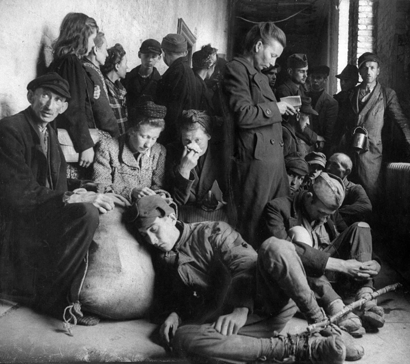 Exhausted, homeless German refugees huddled in a city municipal building seeking shelter. 1945.