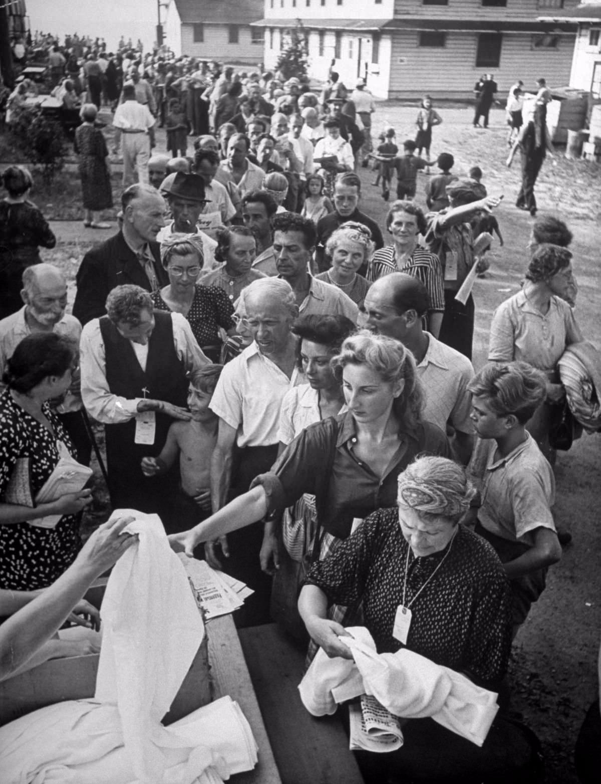 The refugess line up after dinner in front of the mess halls to get two towels and one cake of soap each. Many of them were hesitant to let LIFE photographer Alfred Eisenstaedt take their pictures until they had a chance to clean up. Others were worries by the raggedness of their clothing. They said