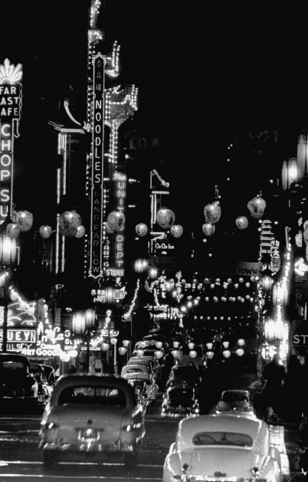 Cars driving through Chinatown at night.