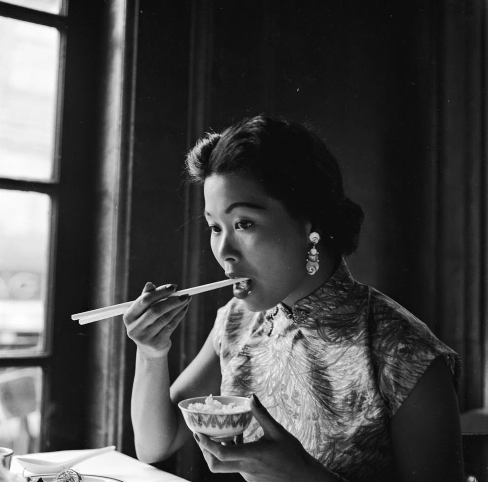 A woman samples a small portion of rice.