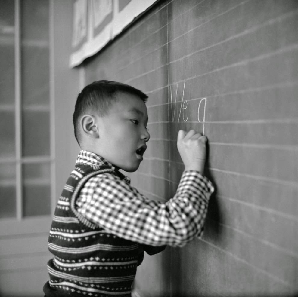 A little boy at the Commodore Stockton School practices writing on the blackboard.