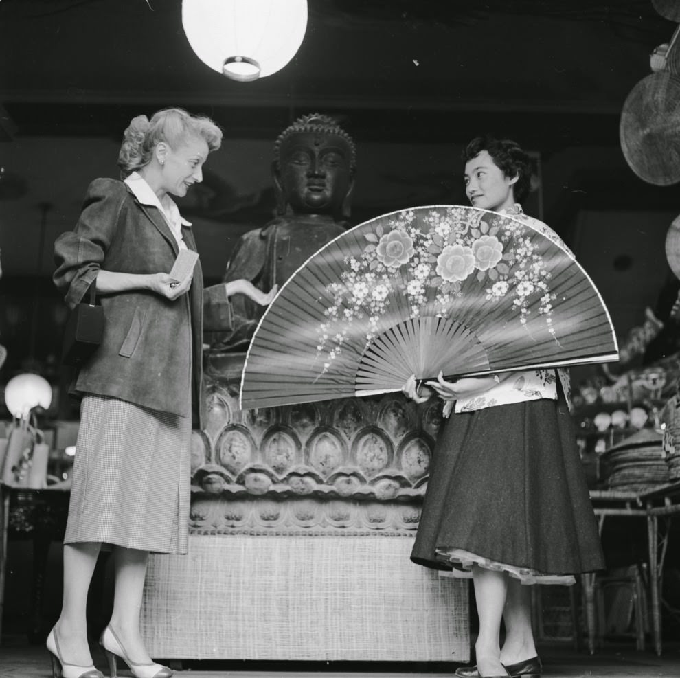 A shop assistant at the Tai Ping Company boutique on Grant Avenue demonstrates a giant Chinese fan to an interested customer.