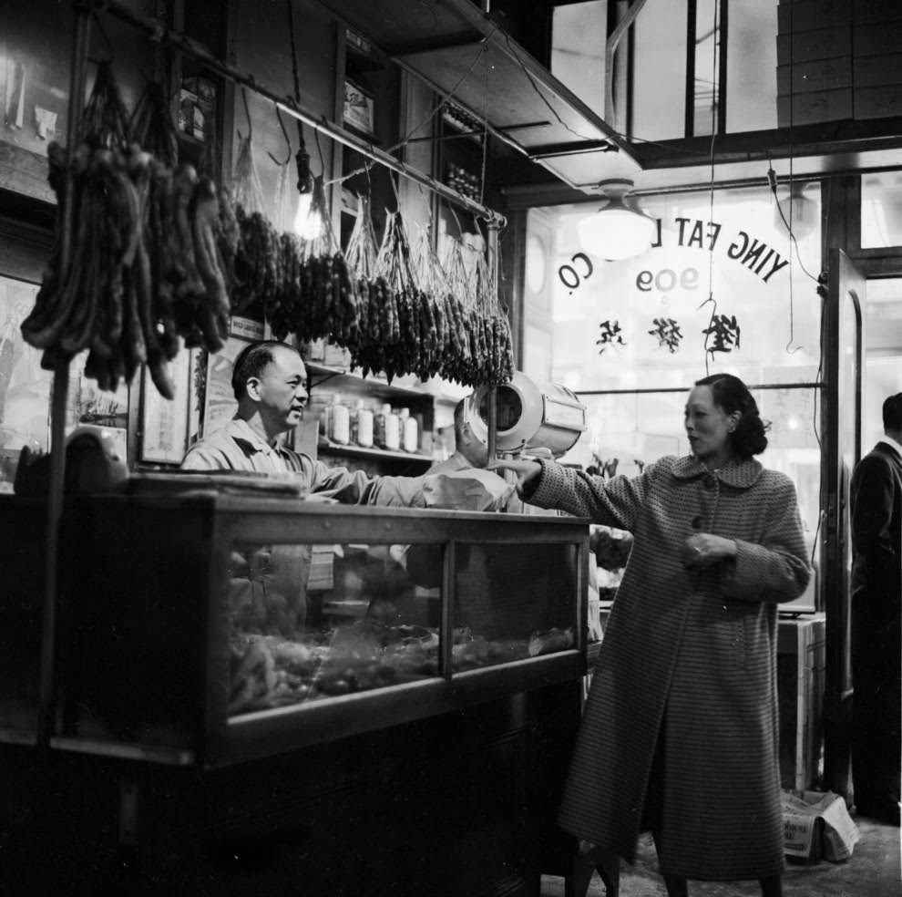 A customer receives her order from the butcher at Ying Fat Lung’s Chinese shop.