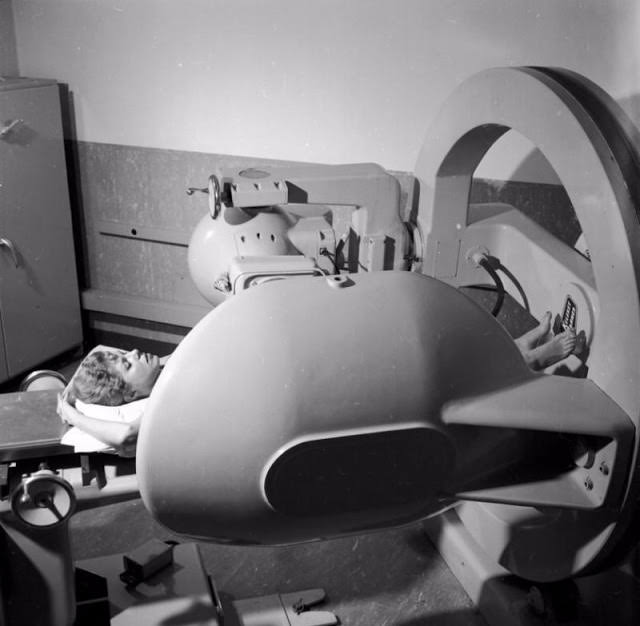 A rotating cobalt machine swinging around the body of a patient, attacking cancerous tumors, 1955.