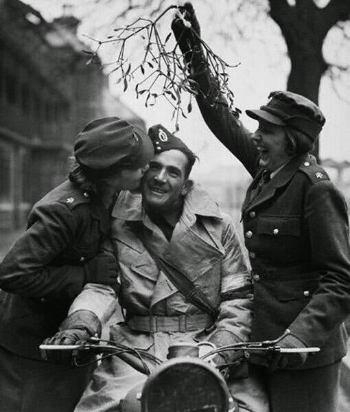 An ATS girl kisses a soldier under some mistletoe held aloft by her friend, while their depot is preparing for Christmas Day. 20th December 1939