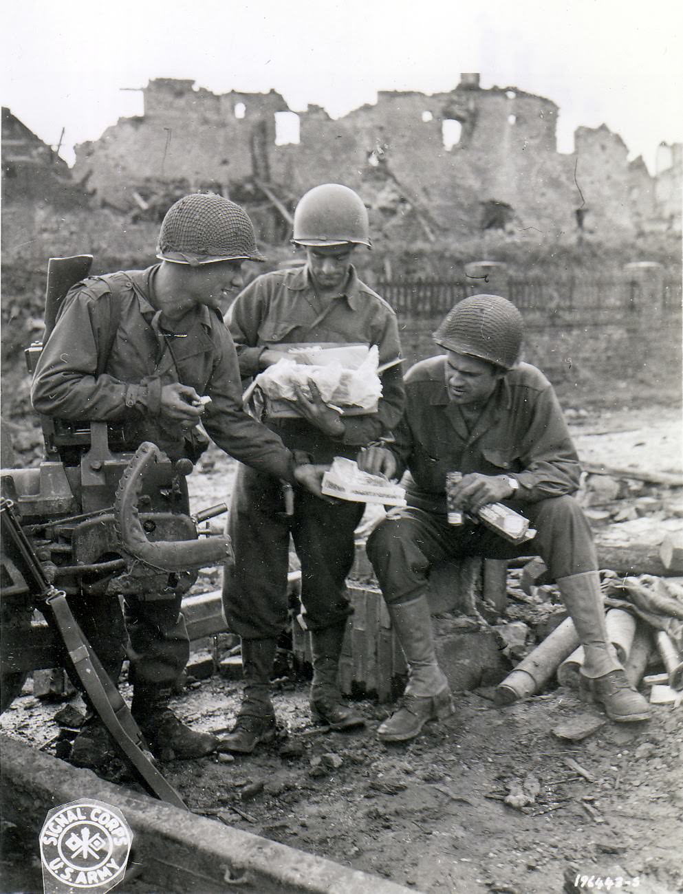 S Army Pfc. Carl Anker, Pfc. Edmund Dill, and Sgt. Ted Bailey sharing the contents of the care package sent by Dill's wife for the Christmas holiday, somewhere in Europe, 18 Nov 1944.